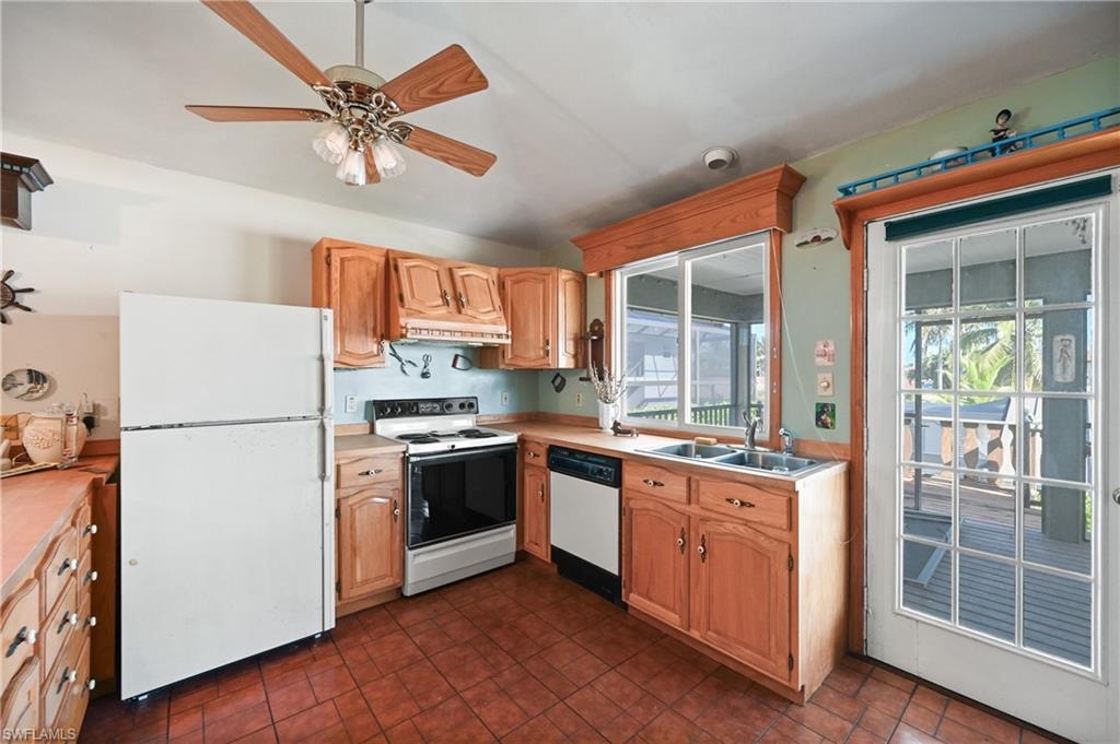 Kitchen with white appliances, light countertops, ceiling fan, premium range hood, and light brown cabinetry