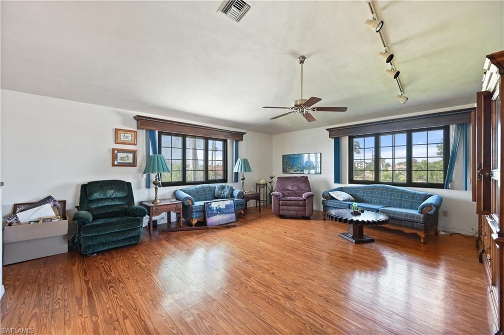 Living area with wood finished floors, ceiling fan, and track lighting