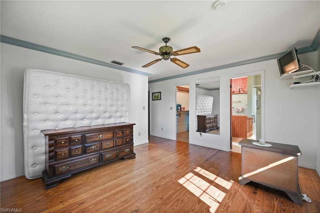 Bedroom with wood finished floors, ceiling fan, and ornamental molding