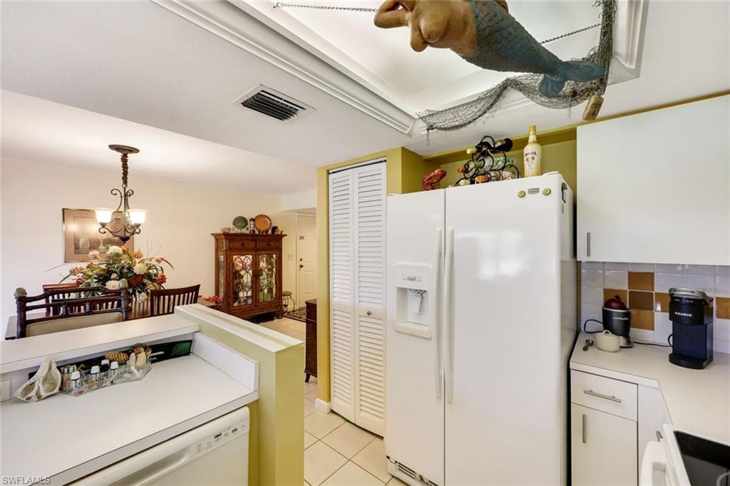 Kitchen featuring visible vents, a chandelier, light countertops, light tile patterned floors, and white appliances