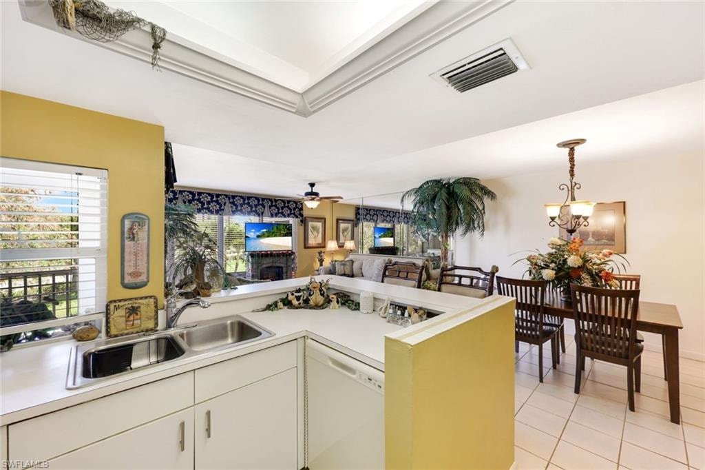 Kitchen featuring visible vents, a sink, a peninsula, white dishwasher, and light countertops