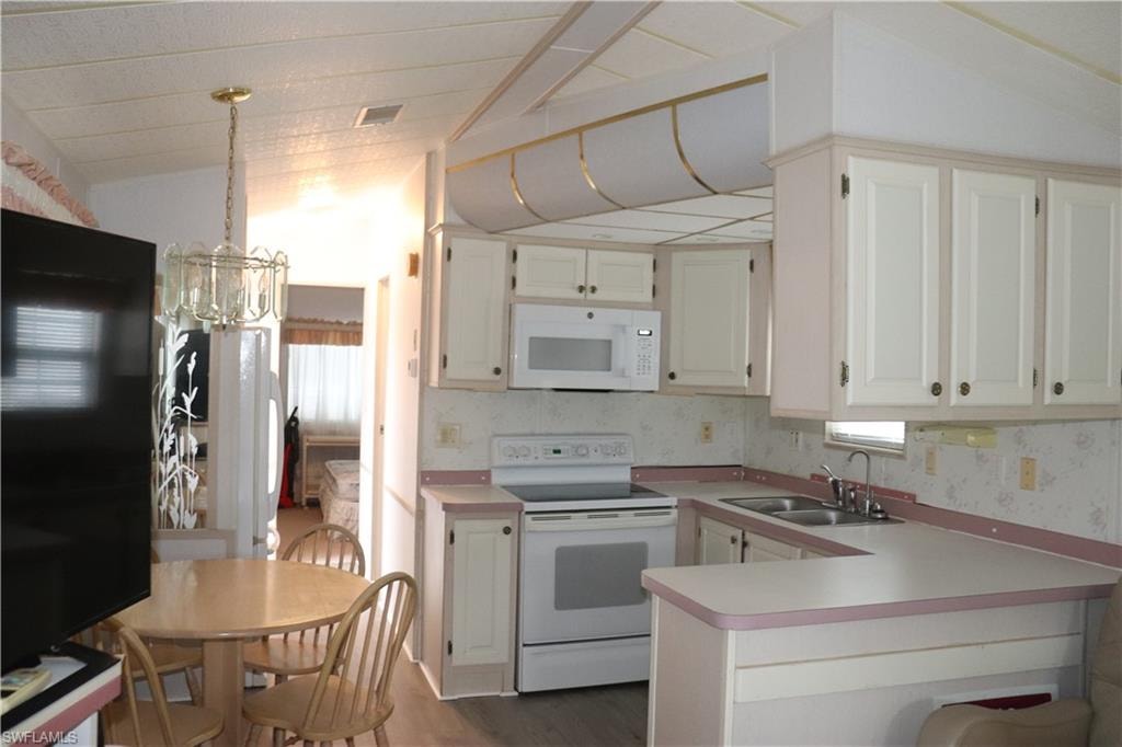 Kitchen featuring light countertops, white appliances, dark wood finished floors, a sink, and visible vents