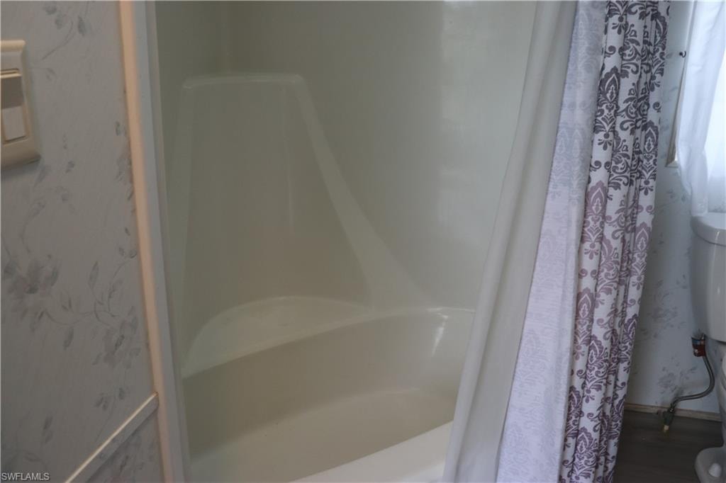 Full bathroom with a shower with curtain and wood finished floors