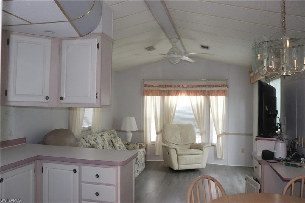 Kitchen featuring lofted ceiling with beams, white cabinets, wood finished floors, and light countertops
