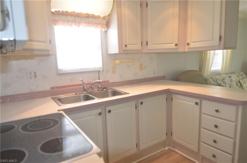 Kitchen with white cabinets, light countertops, and a sink