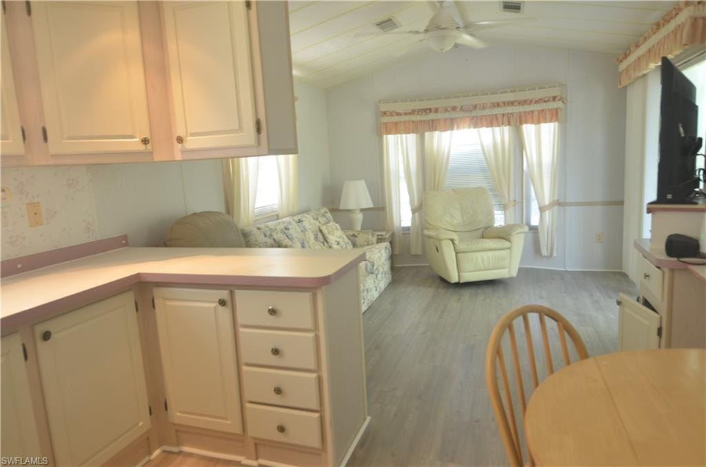 Kitchen featuring vaulted ceiling, light countertops, a peninsula, light wood-style floors, and ceiling fan