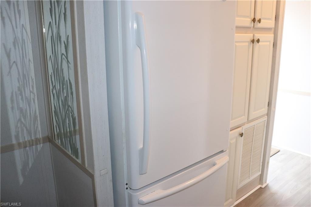 Room details with visible vents, wood finished floors, and freestanding refrigerator