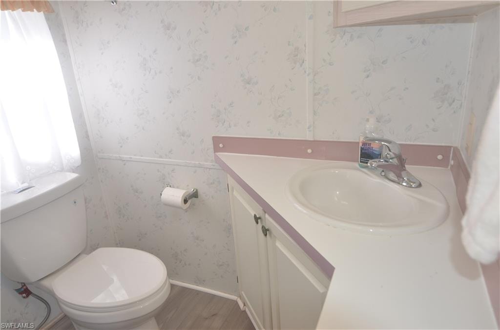 Bathroom with wallpapered walls, toilet, and vanity
