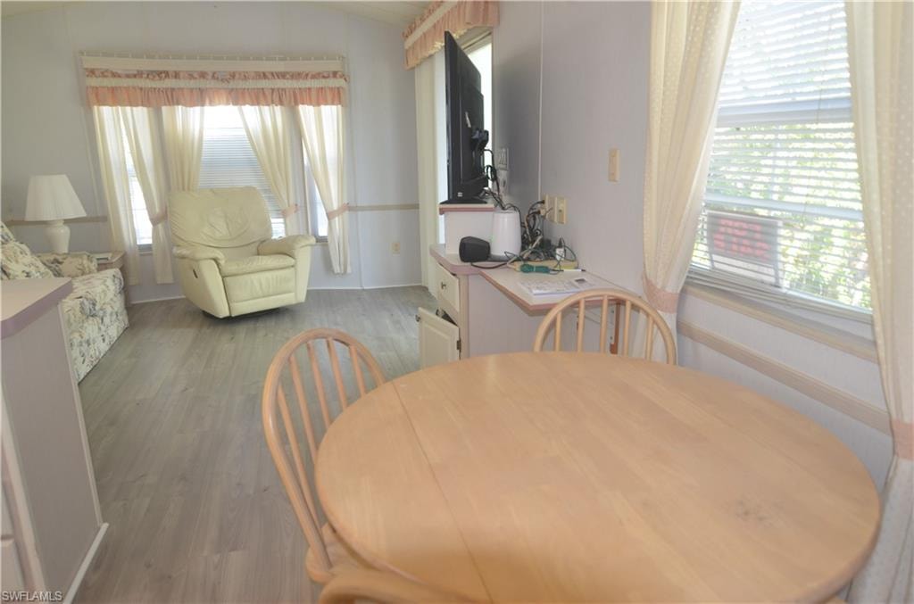 Dining space with vaulted ceiling, light wood-type flooring, and a healthy amount of sunlight