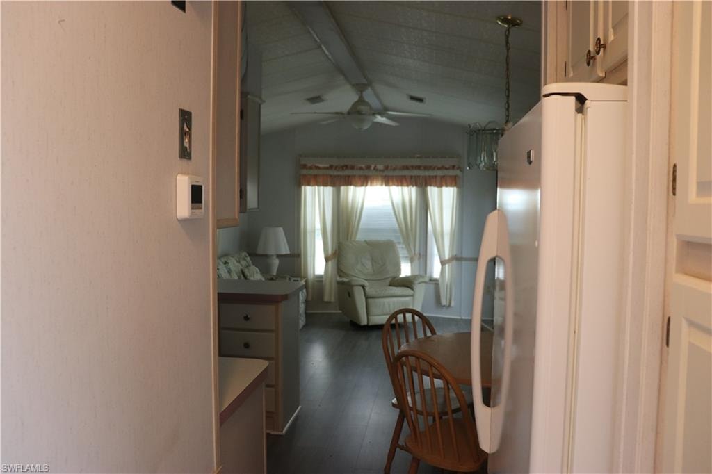 Hallway with dark wood-style floors and lofted ceiling