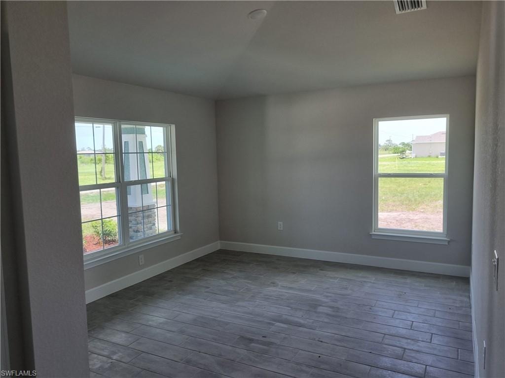 Empty room with dark wood-style flooring and lofted ceiling