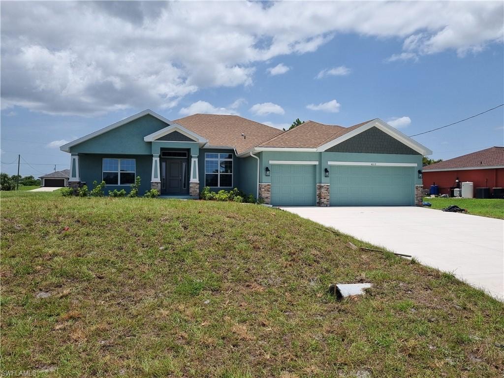View of front of home with a garage, driveway, a front yard, and stone siding