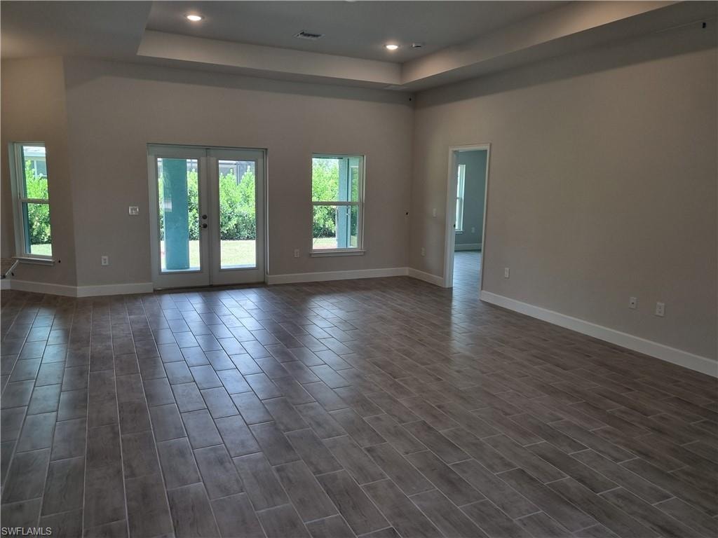 Unfurnished room featuring a tray ceiling, recessed lighting, dark wood finished floors, and french doors