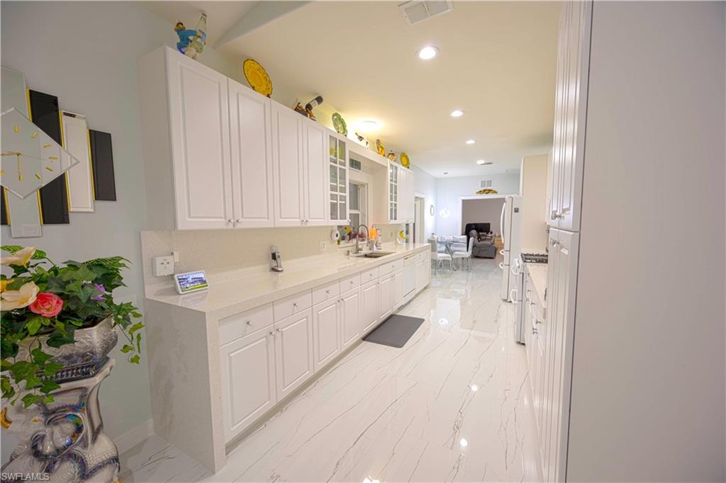 Kitchen featuring visible vents, marble finish floor, a sink, and white cabinetry