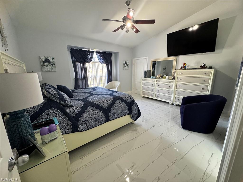 Bedroom with marble finish floor, lofted ceiling, and ceiling fan