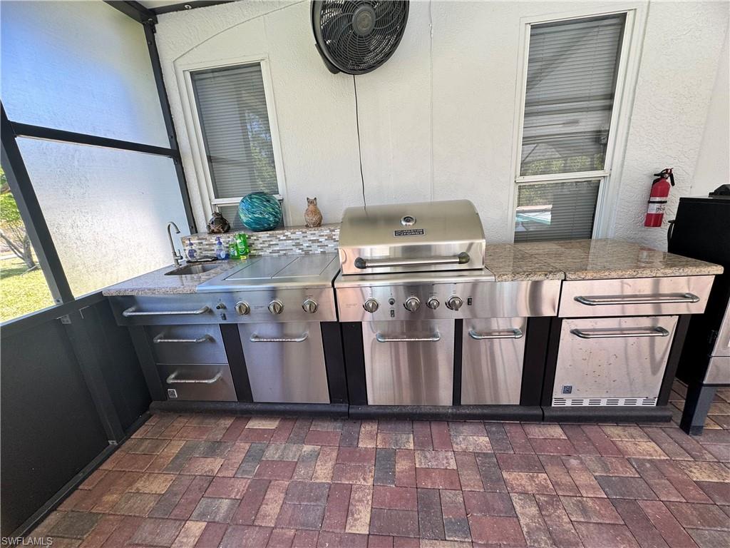 View of patio / terrace featuring a sink, an outdoor kitchen, and a lanai