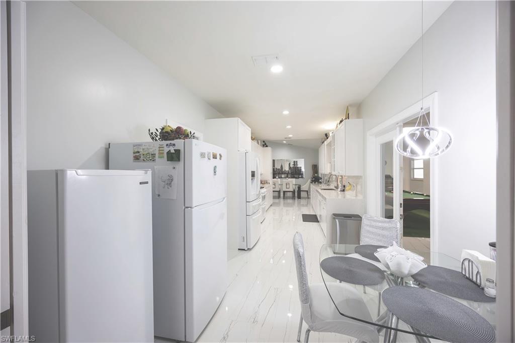 Kitchen featuring white cabinets, a sink, light countertops, and freestanding refrigerator