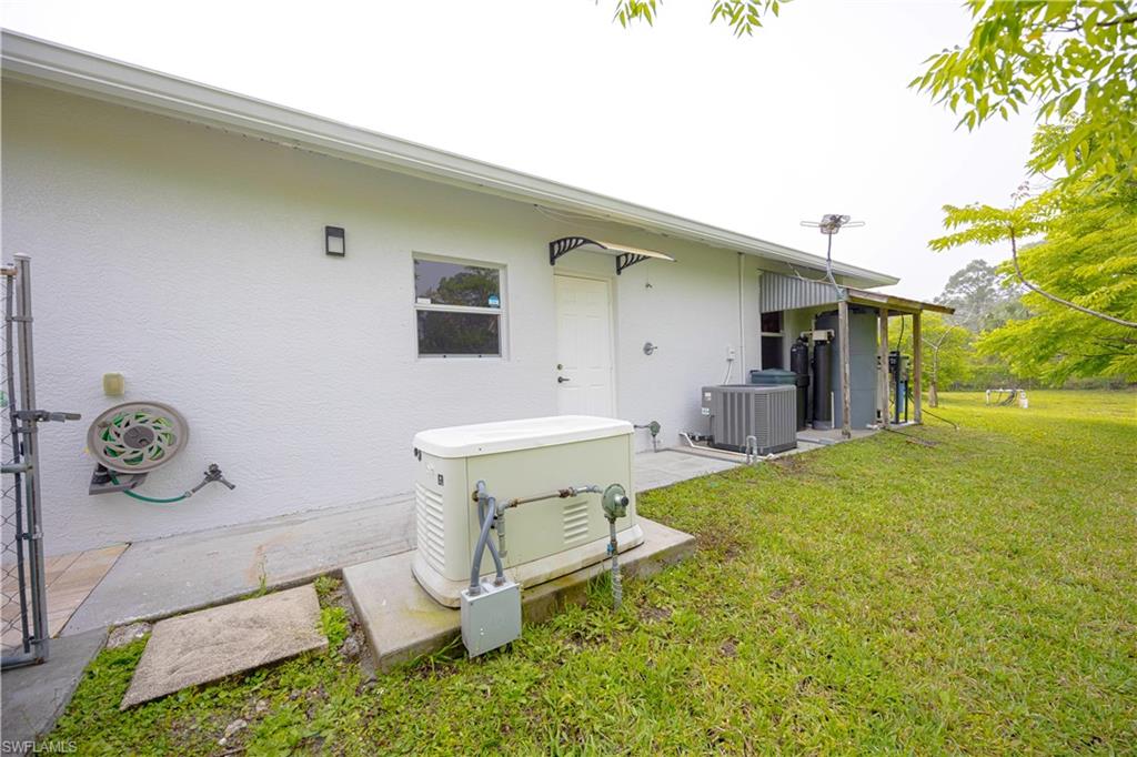 Rear view of property with central air condition unit, stucco siding, and a lawn