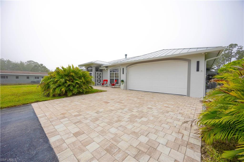 View of front of house featuring a standing seam roof, stucco siding, decorative driveway, metal roof, and an attached garage