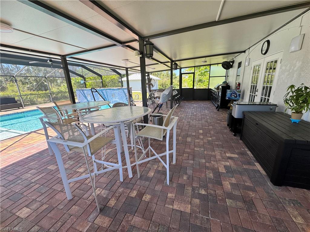 View of patio / terrace featuring french doors, an outdoor pool, outdoor dining area, and glass enclosure