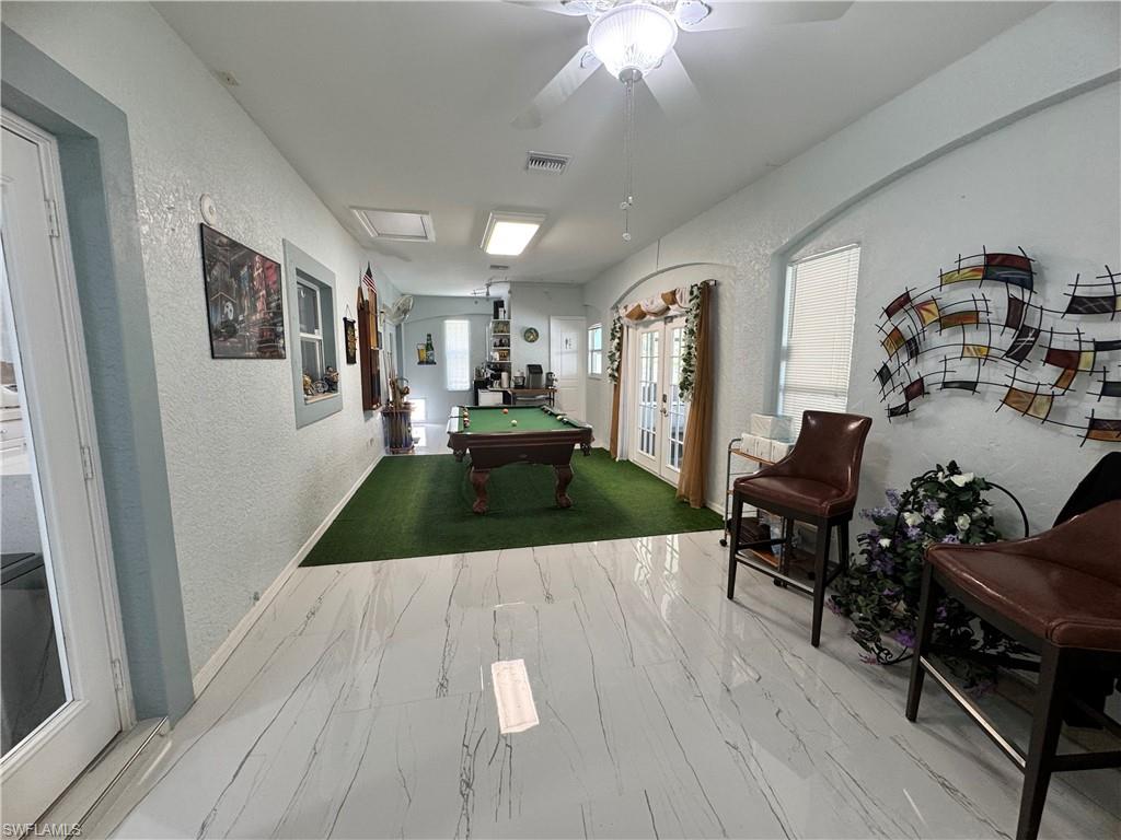 Game room with a textured wall, marble finish floor, visible vents, a ceiling fan, and pool table