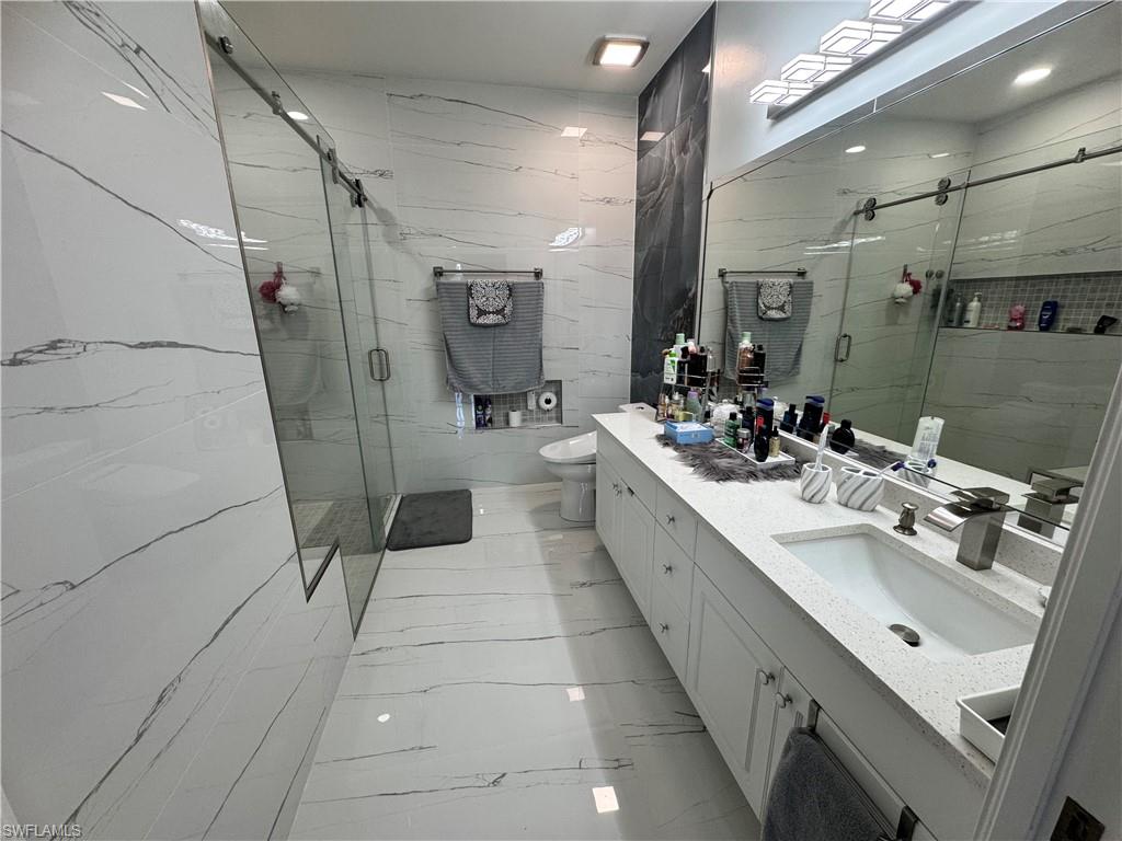 Bathroom with a shower stall, marble finish floor, toilet, and vanity
