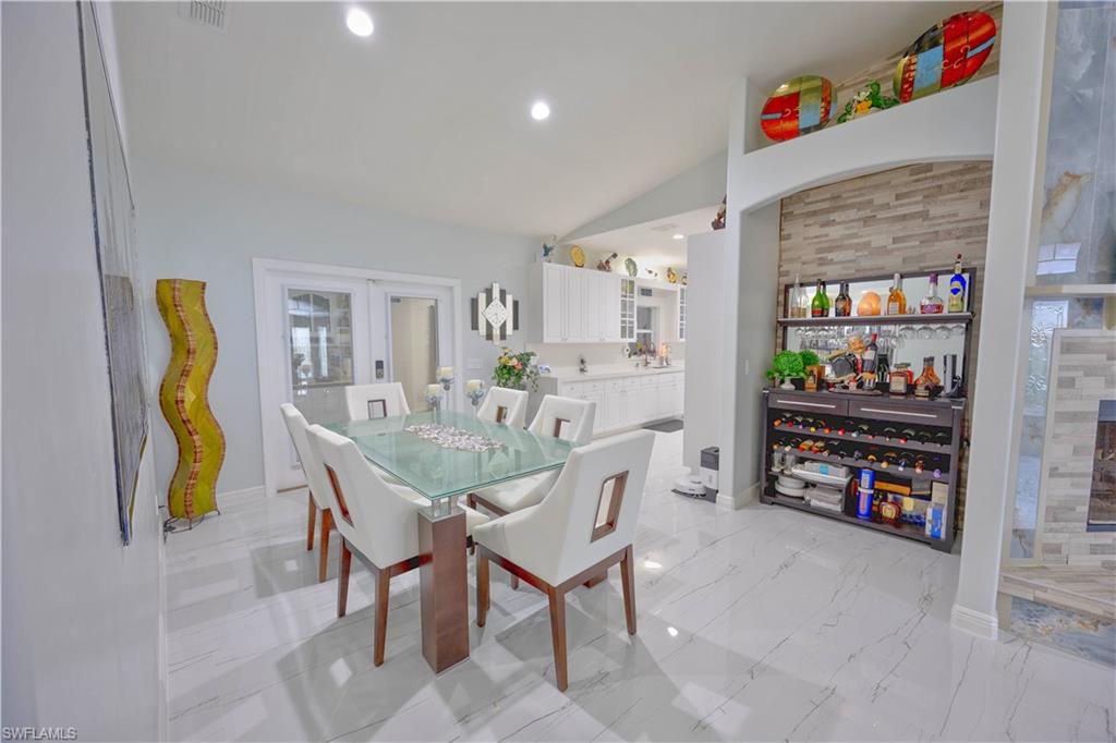 Dining area with baseboards, vaulted ceiling, recessed lighting, french doors, and marble finish floor