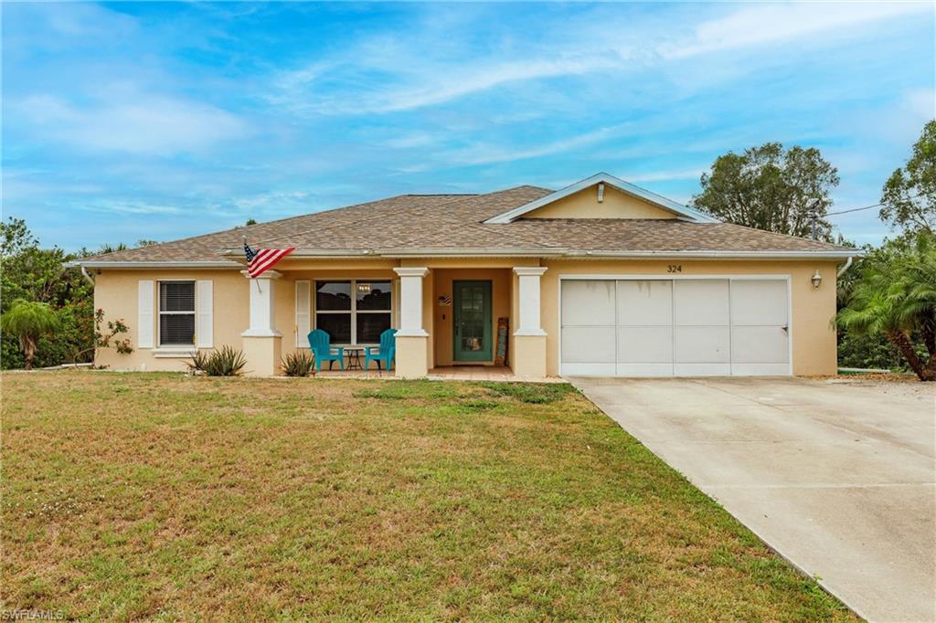 Ranch-style home featuring a front yard, stucco siding, a garage, and driveway