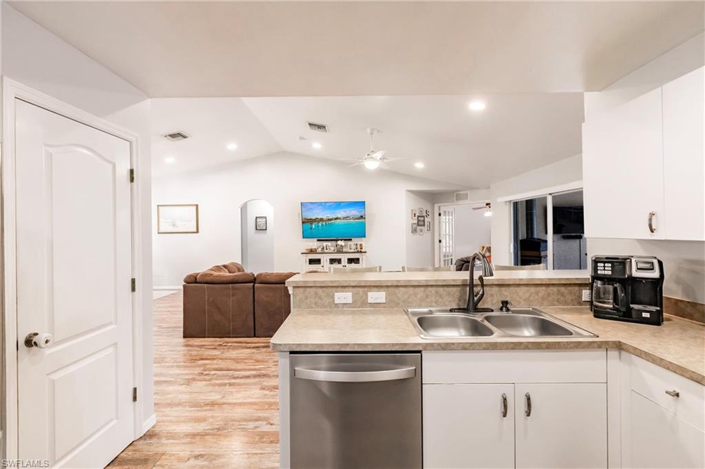 Kitchen featuring open floor plan, a sink, ceiling fan, dishwasher, and a peninsula