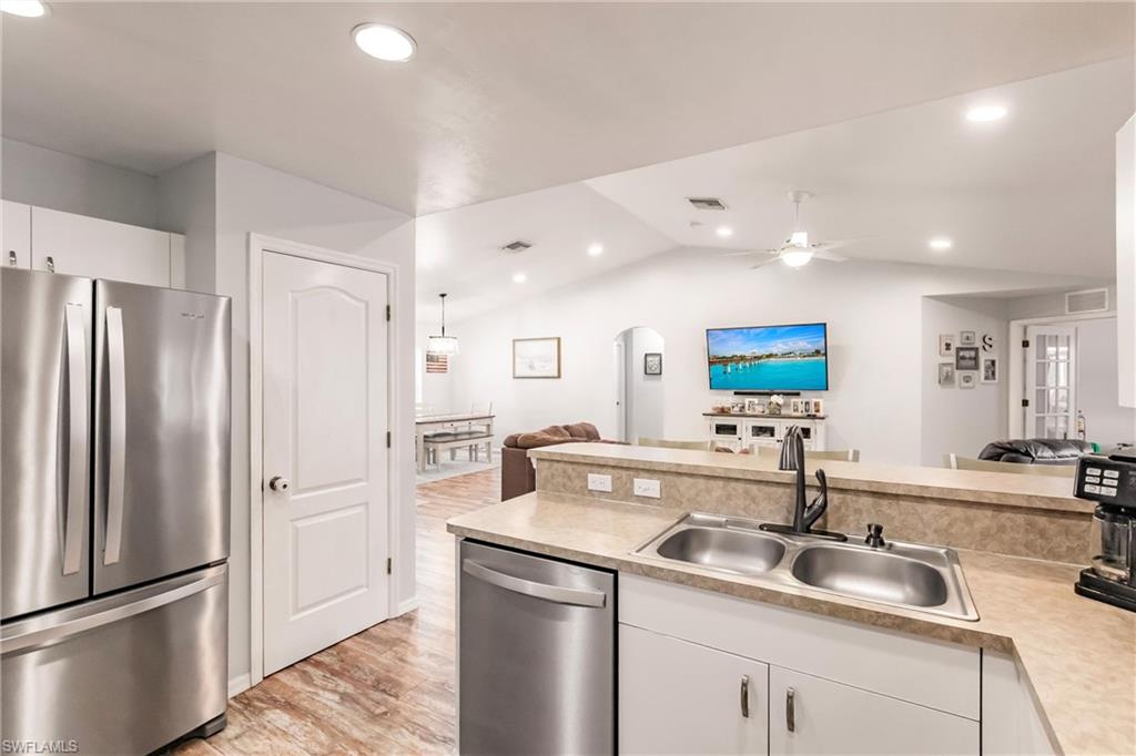 Kitchen featuring light countertops, appliances with stainless steel finishes, arched walkways, a sink, and open floor plan
