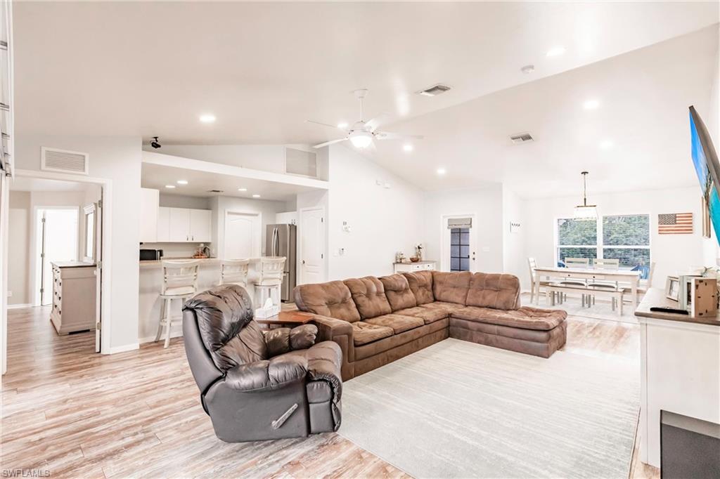 Living room featuring vaulted ceiling, recessed lighting, light wood finished floors, and a ceiling fan