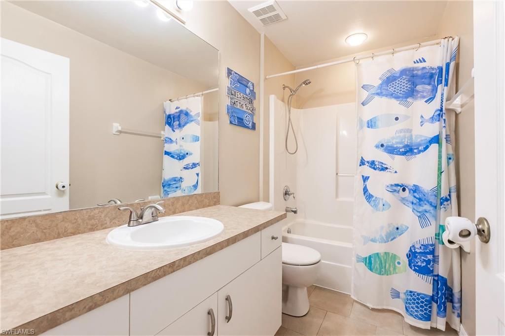 Full bath featuring tile patterned floors, toilet, vanity, shower / bath combo