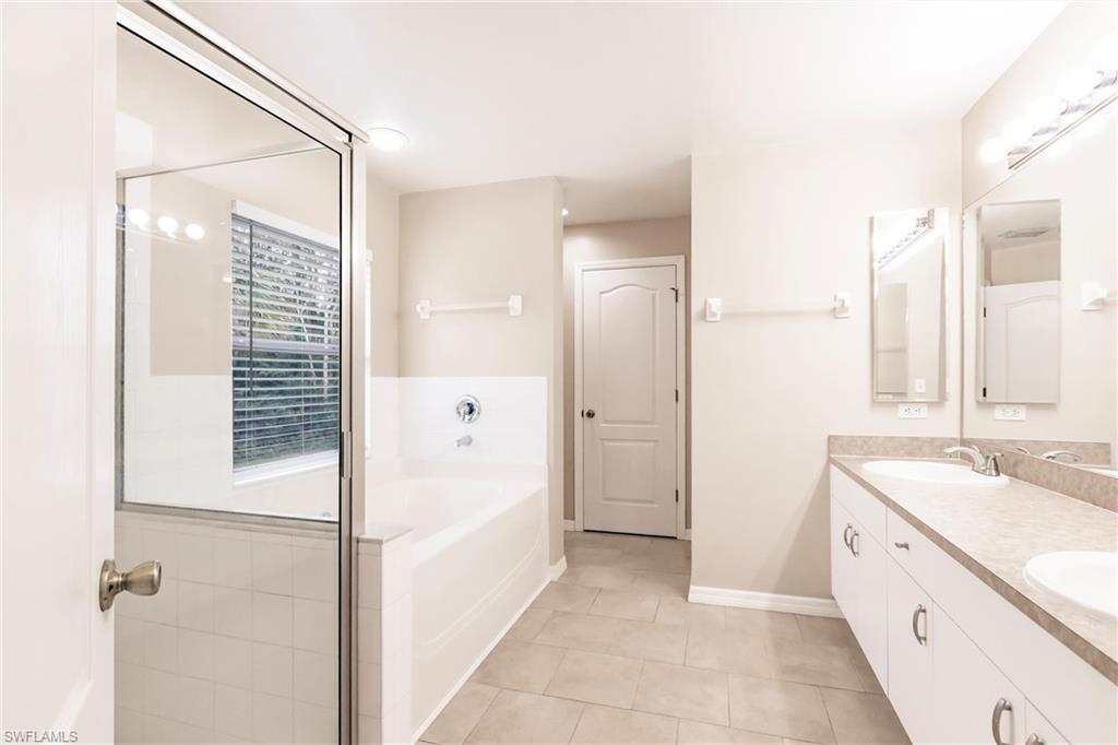 Full bath featuring tile patterned floors, double vanity, a sink, and a garden tub
