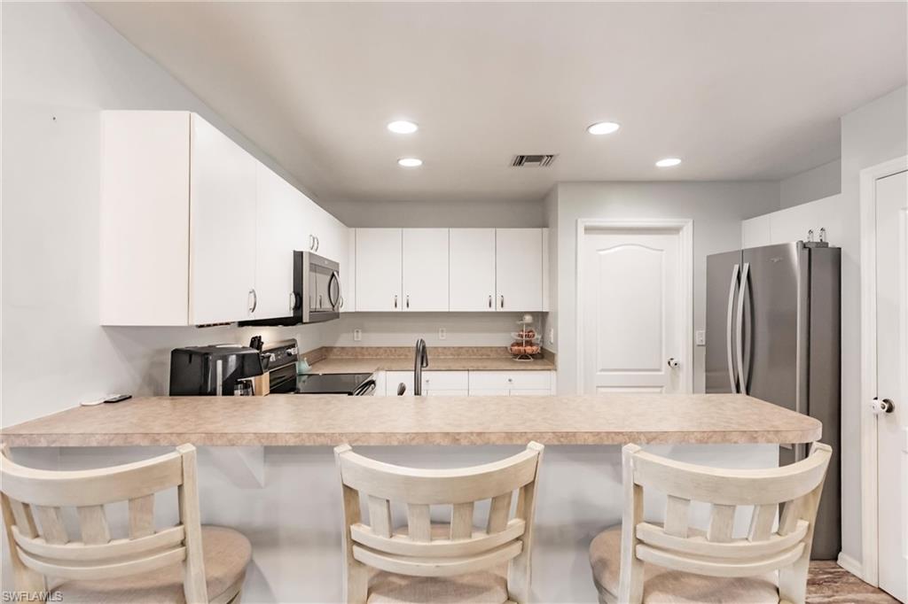 Kitchen featuring light countertops, recessed lighting, stainless steel appliances, and a peninsula