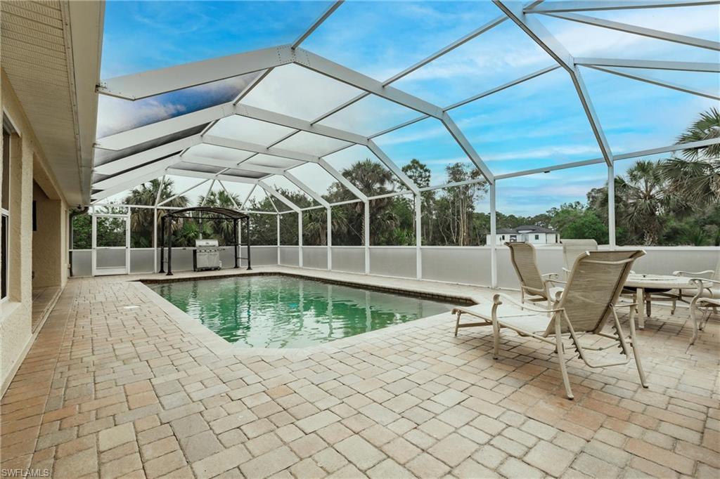 Outdoor pool with grilling area, a lanai, and a patio area