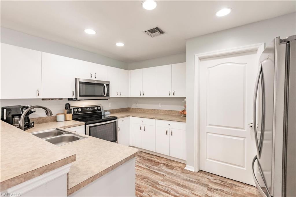 Kitchen featuring light countertops, light wood-style flooring, appliances with stainless steel finishes, and a sink