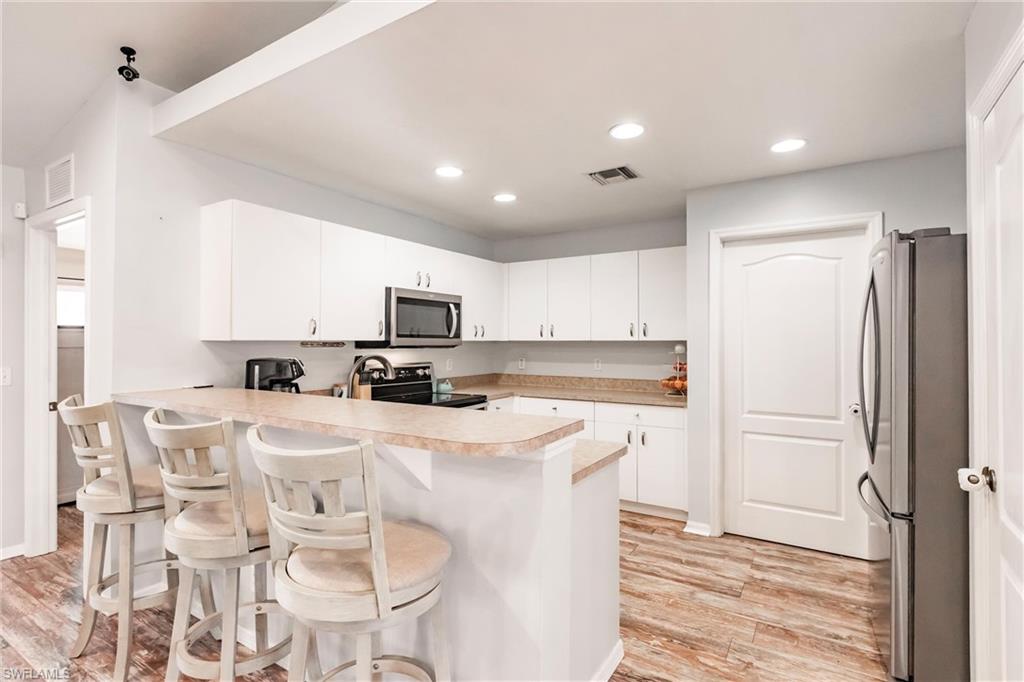 Kitchen with light countertops, light wood-style flooring, a peninsula, and appliances with stainless steel finishes