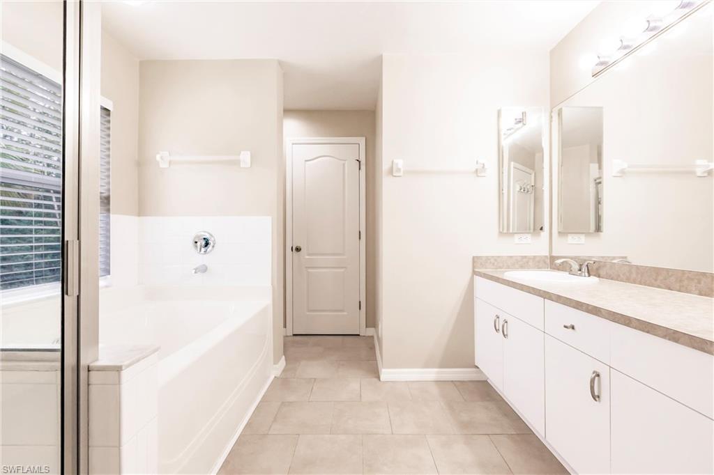 Full bath with baseboards, a garden tub, tile patterned floors, and vanity