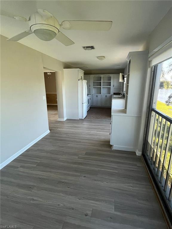 Hallway featuring a sink, baseboards, visible vents, and dark wood-type flooring
