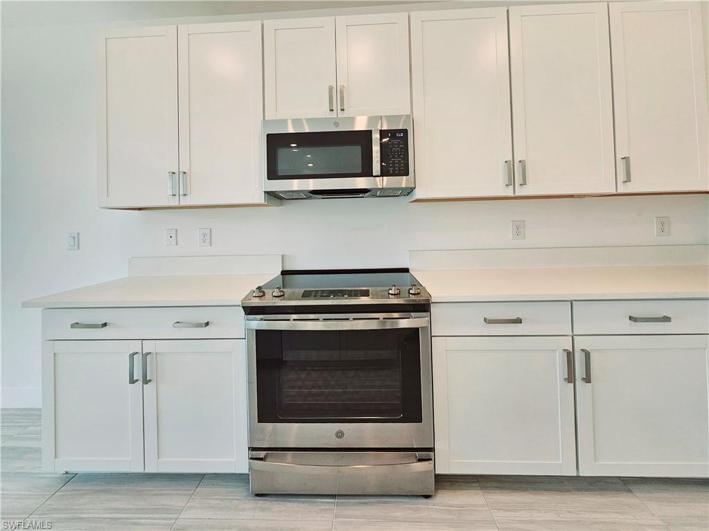 Kitchen featuring appliances with stainless steel finishes, light countertops, and white cabinets