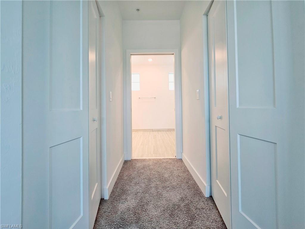 Corridor featuring carpet floors and baseboards