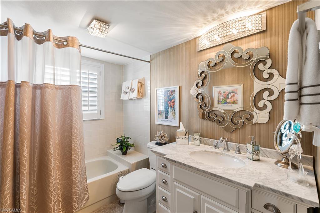remodeled 2nd bathroom offers a free standing marble top vanity, shower/tub combo, custom mirror and lighting, plantation shutters.