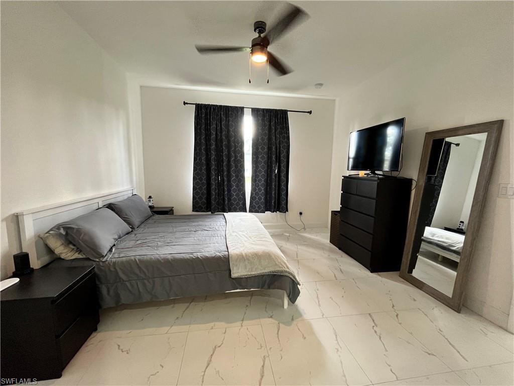 Bedroom with light marble finish floors and a ceiling fan