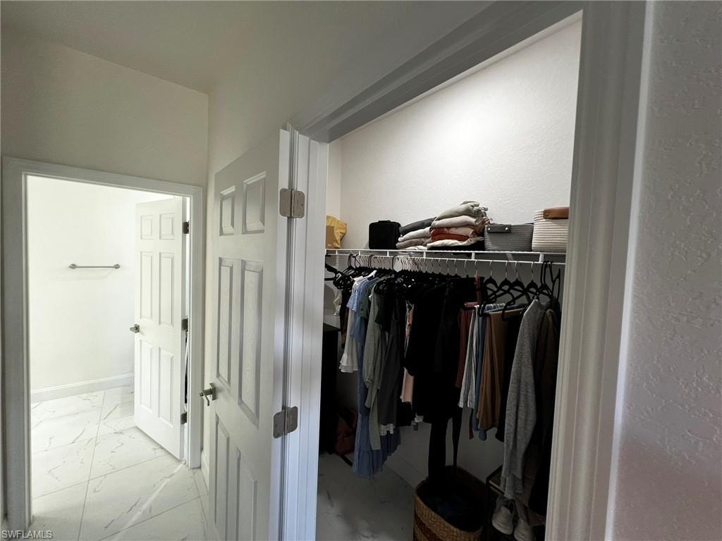 Spacious closet featuring marble finish floor