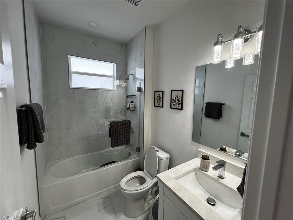 Bathroom with marble finish floor, toilet, vanity, and shower / bath combination