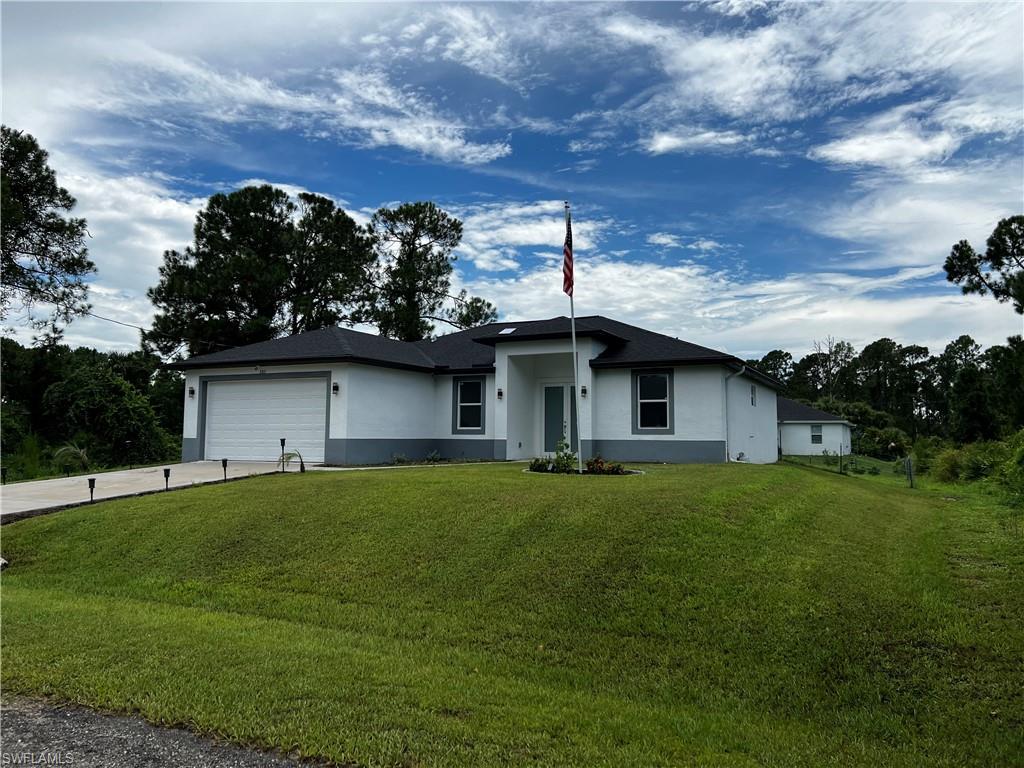 View of front facade with a garage, stucco siding, concrete driveway, and a front yard