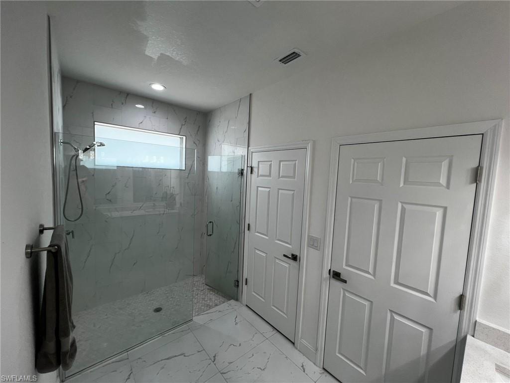 Bathroom with marble finish floor, a marble finish shower, and visible vents