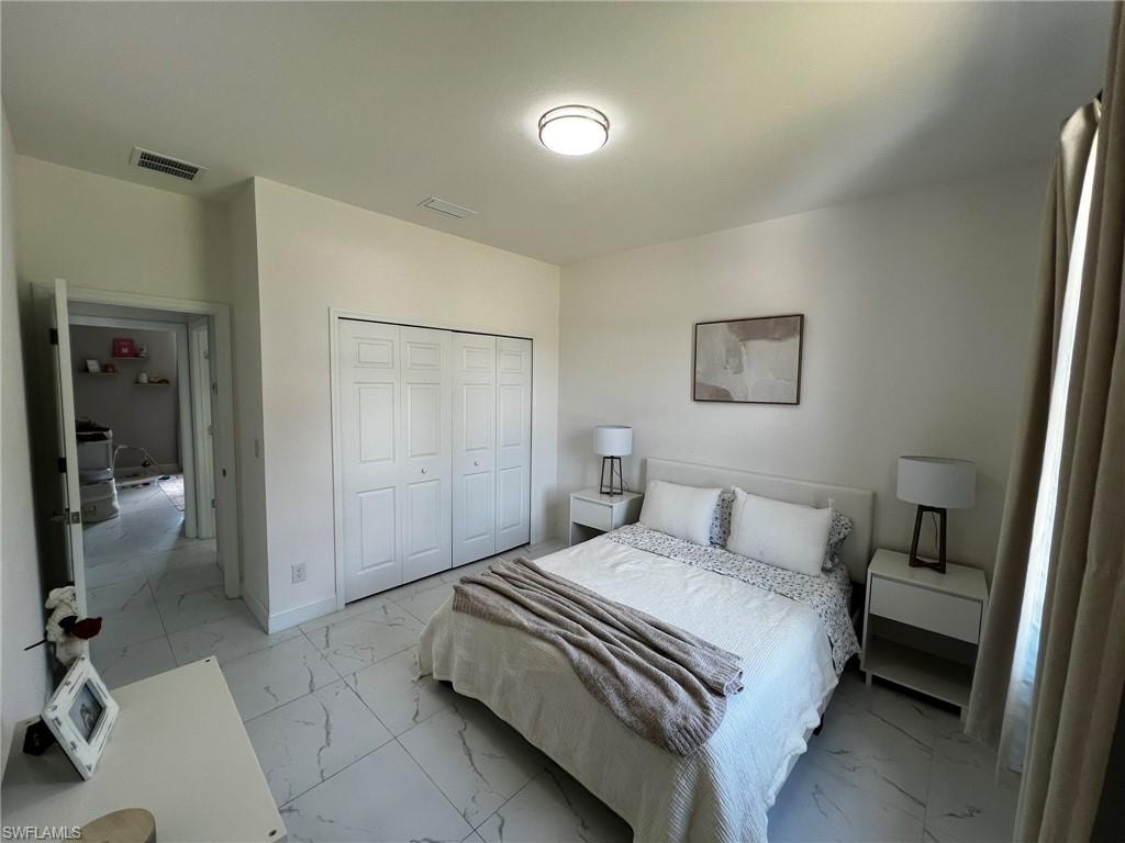 Bedroom with visible vents, marble finish floor, and a closet