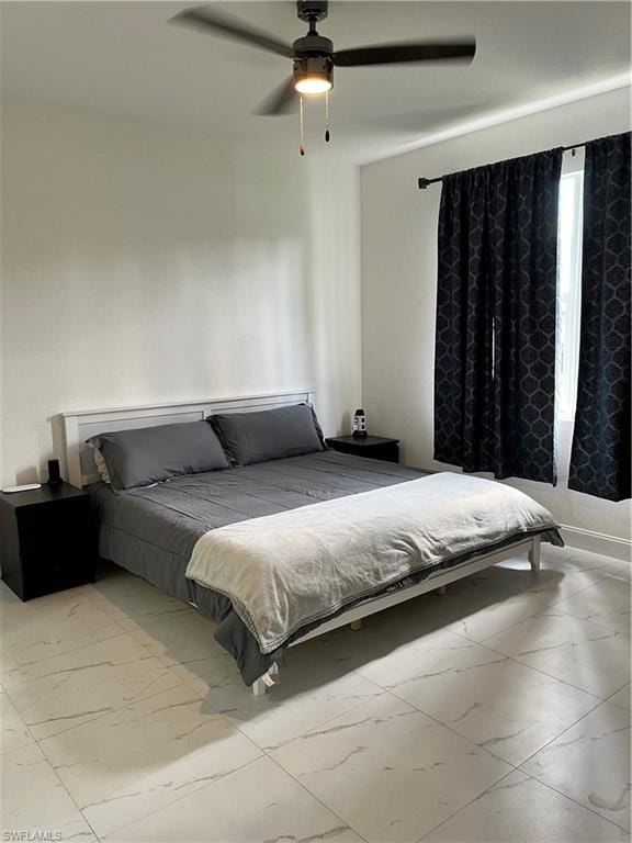 Bedroom featuring marble look tiles and ceiling fan