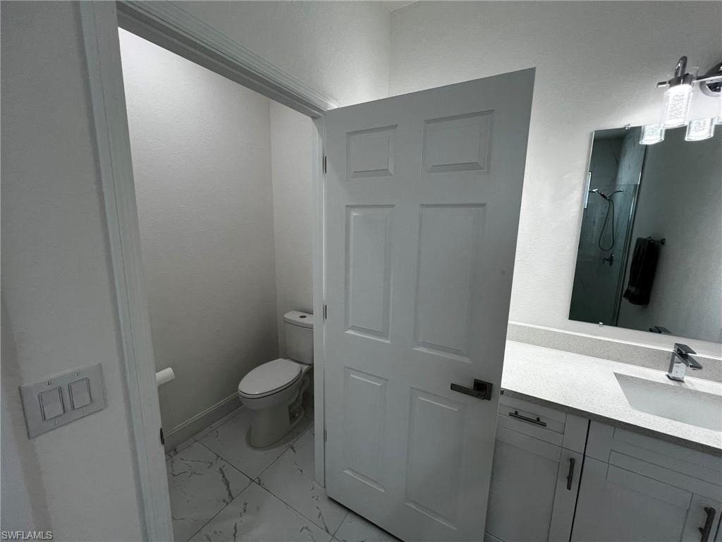 Full bath with a shower, marble finish floor, vanity, and toilet